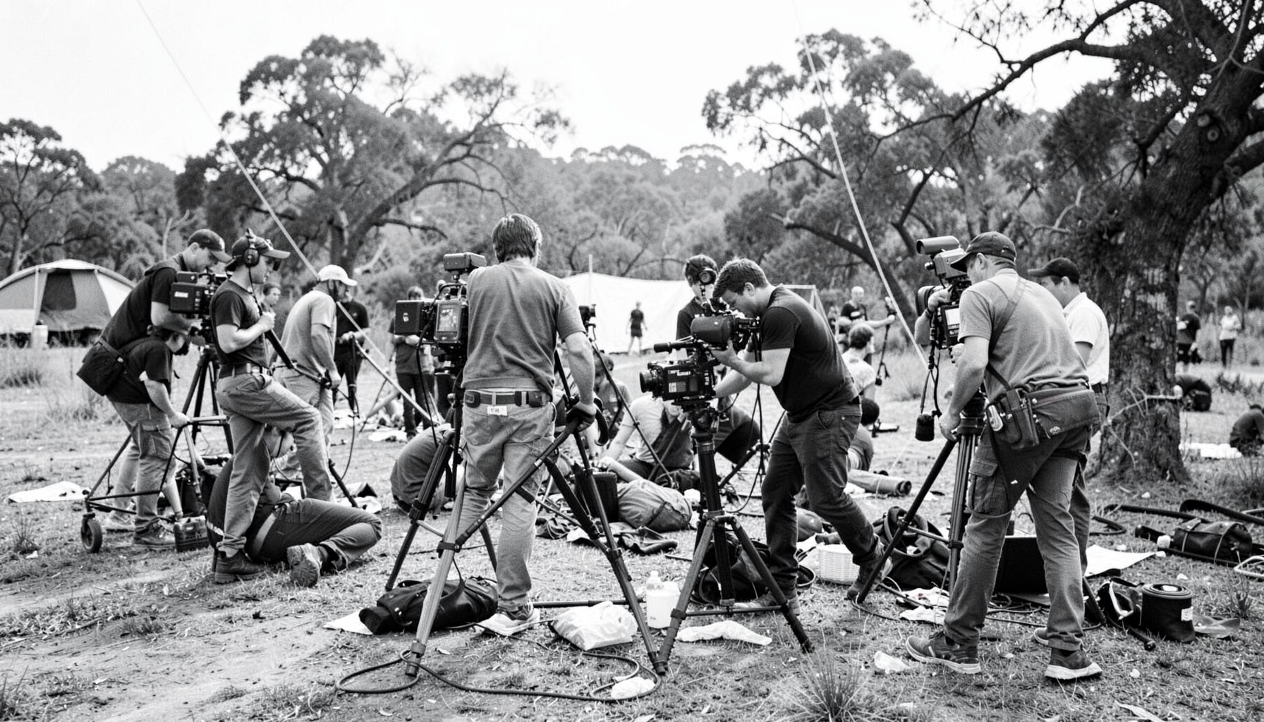 A film crew setting up equipment in an outdoor location, black and white photograph with a documentary and collaborative atmosphere